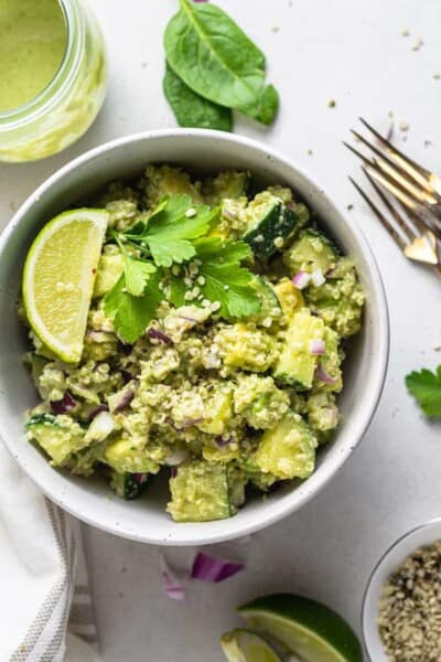 white bowl with cucumber avocado quinoa salad with lime and cilantro