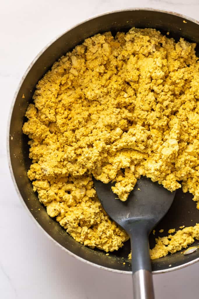 This 10-minute tofu scramble recipe is a satisfying plant-based breakfast with nutritional yeast, turmeric, and garlic for spice and flavor. Overhead of a tofu scramble in a skillet with a spatula.