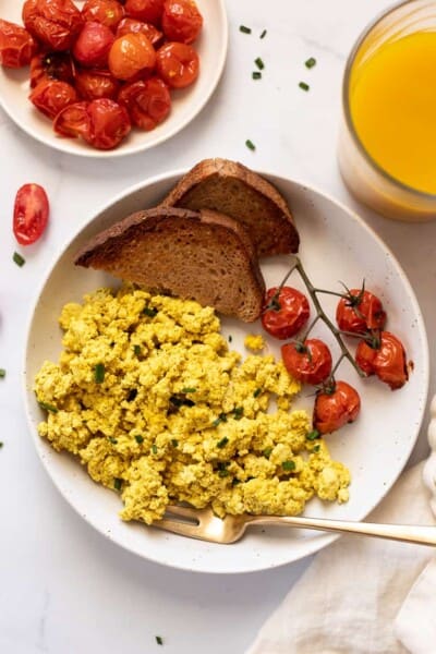 overhead of a white plate with basic tofu scramble with roasted tomatoes and two slices of wheat toast