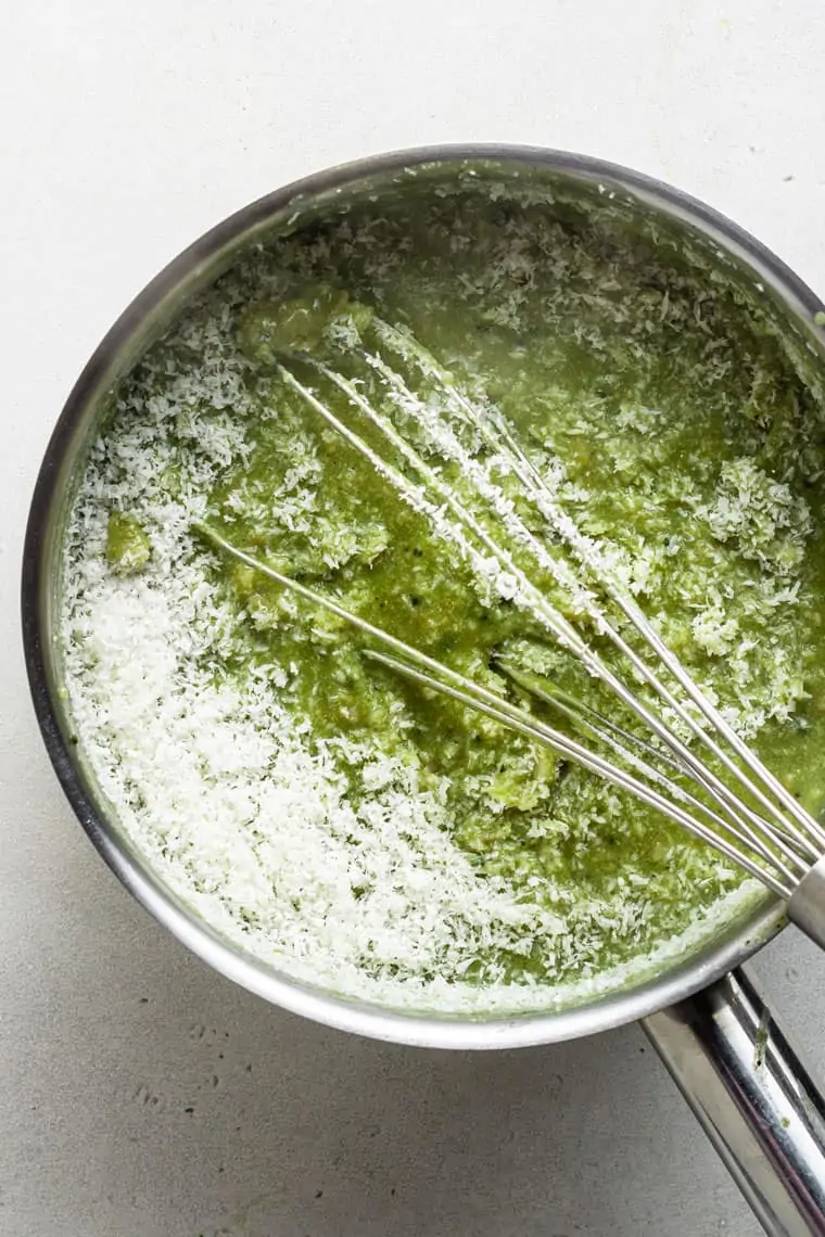 overhead of a silver pot with a whisk stirring coconut into green tea oatmeal