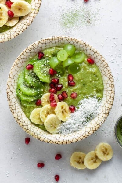 overhead of a bowl with matcha oatmeal topped with coconut flakes and fresh fruit