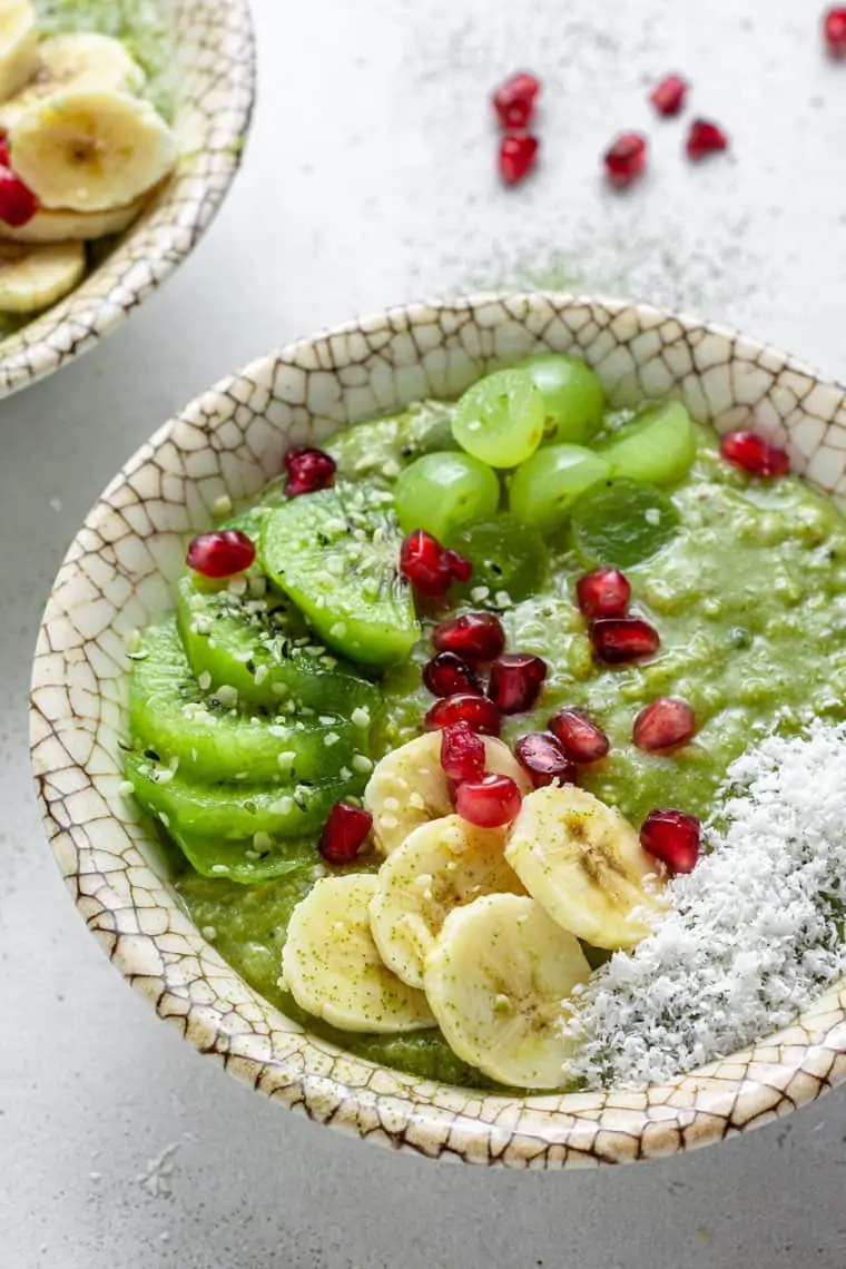 close up on a bowl with green matcha oatmeal topped with bananas, kiwi and pineapple