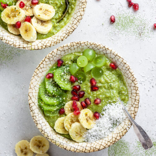 overhead of two bowls with green matcha oatmeal with fresh fruit on top