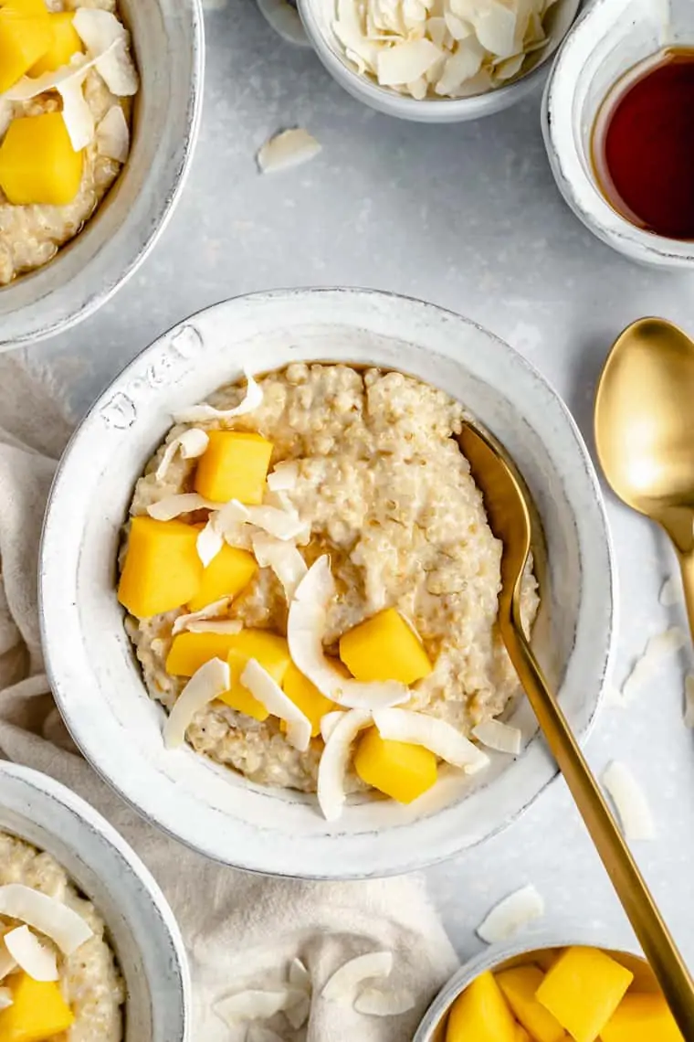 close up on a bowl of steel cut oats with coconut chips and mango cubes