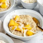 close up on a bowl of coconut steel cut oats with mango and coconut chips on top