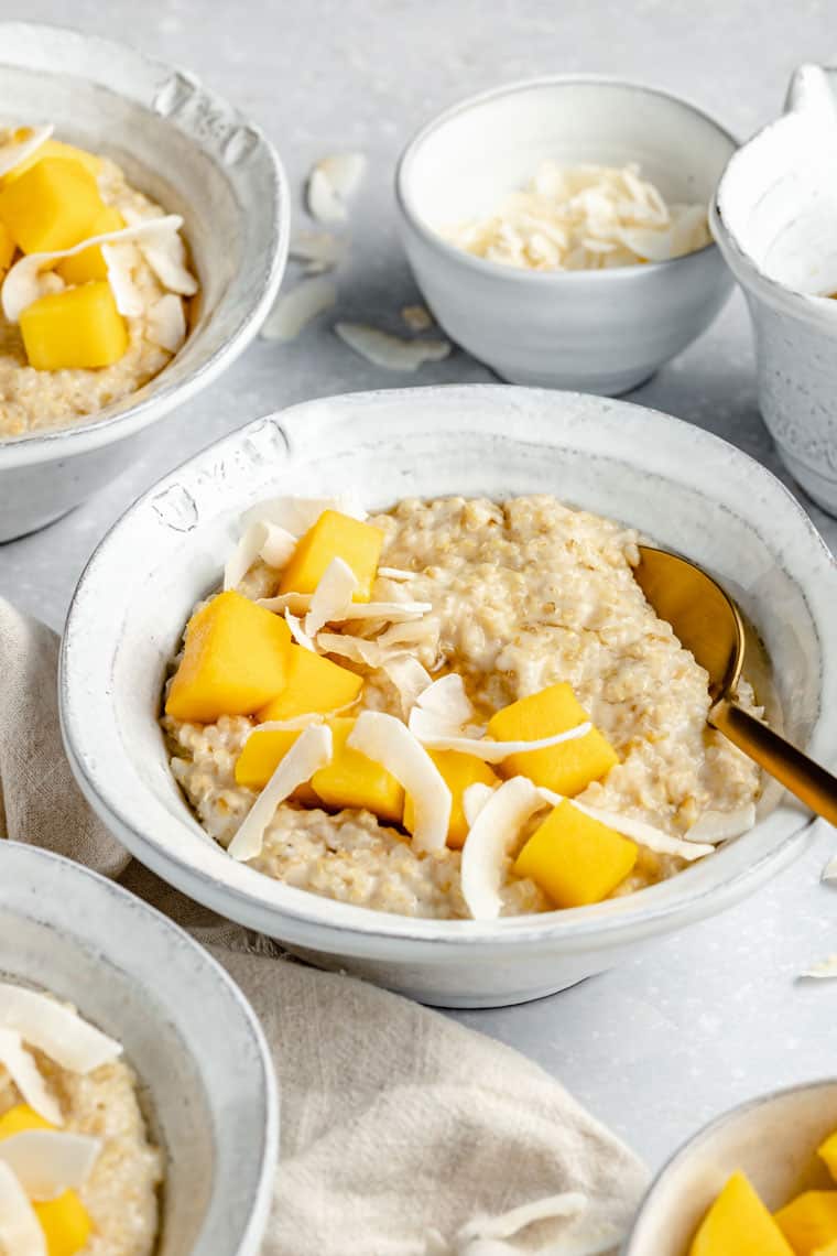 close up on a bowl of coconut steel cut oats with mango and coconut chips on top