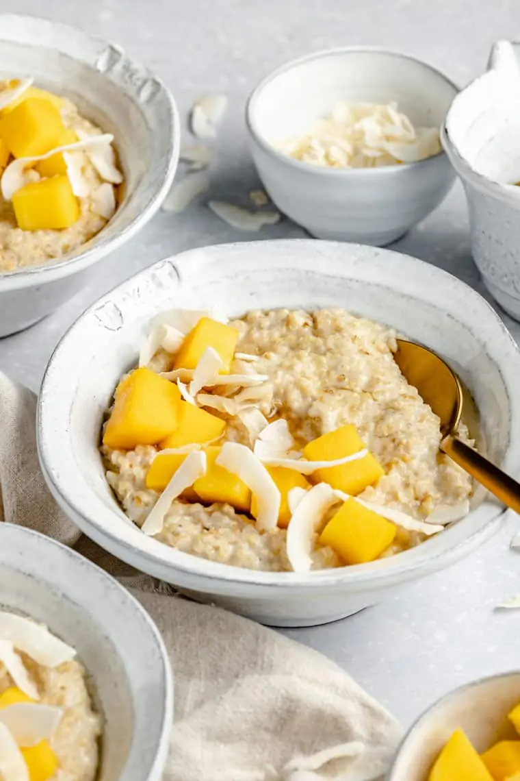 close up on a bowl of coconut steel cut oats with mango and coconut chips on top