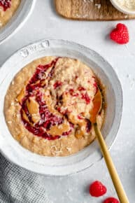 overhead of a bowl of creamy oatmeal with peanut butter, jelly and coconut on top