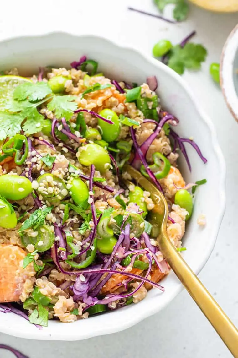 close up of a white bowl with vegetable quinoa salad with asian dressing