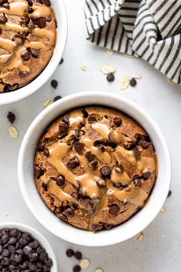 overhead of white bowl with blended vegan baked oatmeal topped with chocolate chips and almond butter