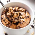 close up on a white bowl with vegan baked oatmeal with silver spoon and inside bite