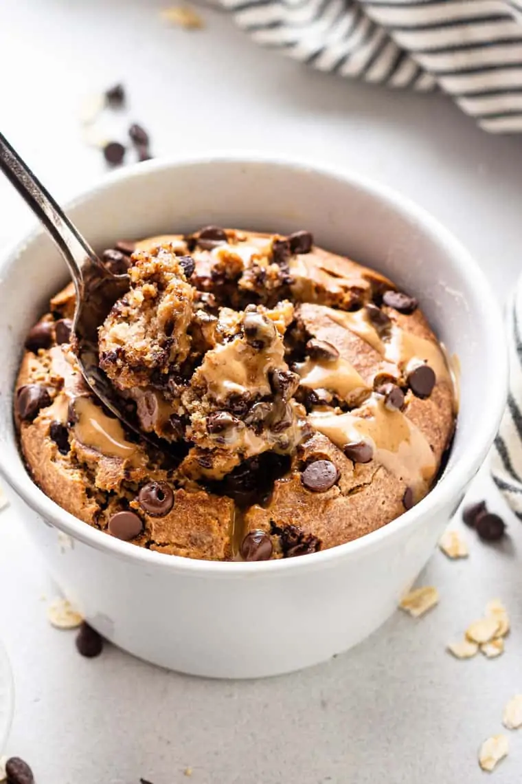 close up on a white bowl with vegan baked oatmeal with silver spoon and inside bite