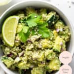white bowl with cucumber avocado quinoa salad with lime and cilantro