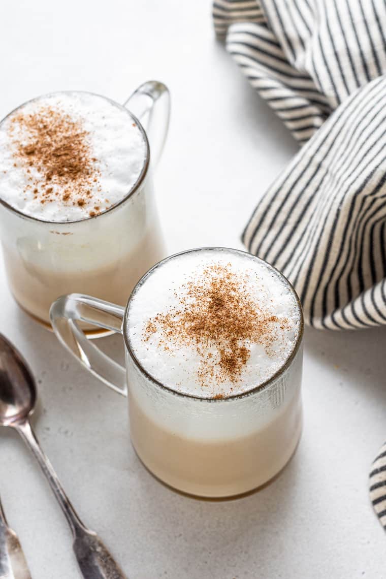 Overhead of two glass mugs with creamy london fog lattes with cinnamon on top