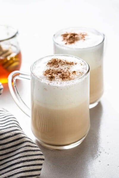 side view of two glass mugs of london fog lattes topped with cinnamon