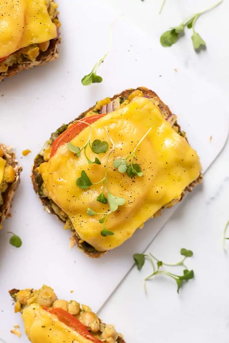 overhead of a piece of gread with chickpeas and vegan cheese melted