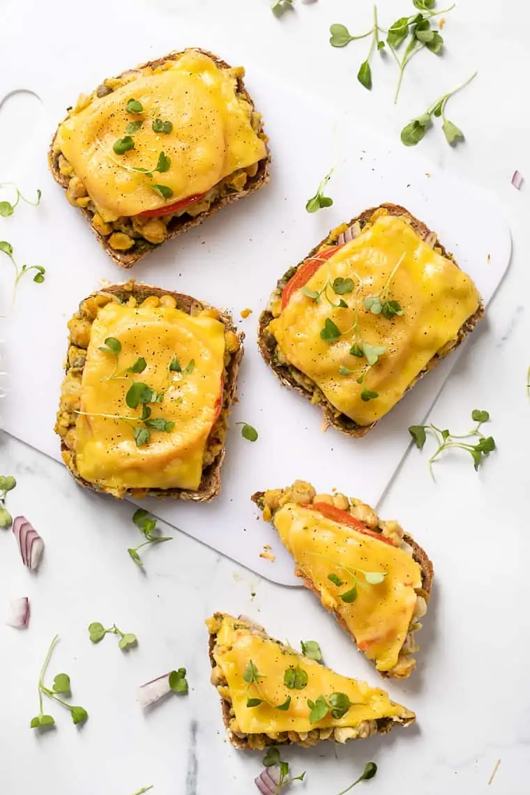 overhead of four open-face vegan chickpea melts with sprouts ontop