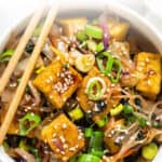 overhead of a white bowl with crispy tofu egg roll topped with sesame seeds