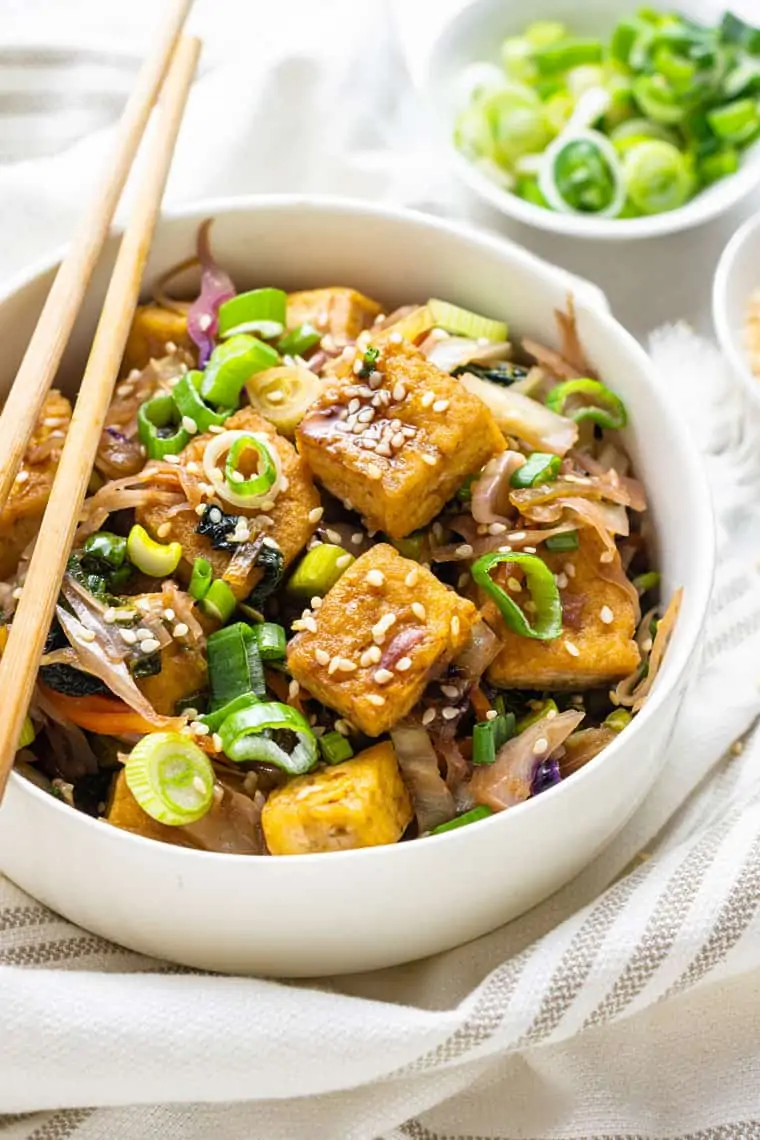 overhead of a white bowl with crispy tofu egg roll topped with sesame seeds