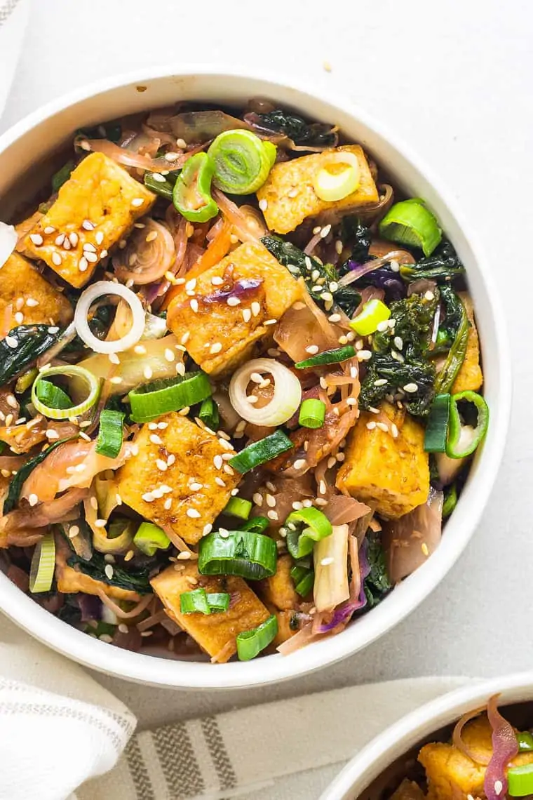 overhead of a white bowl with vegan tofu and greens