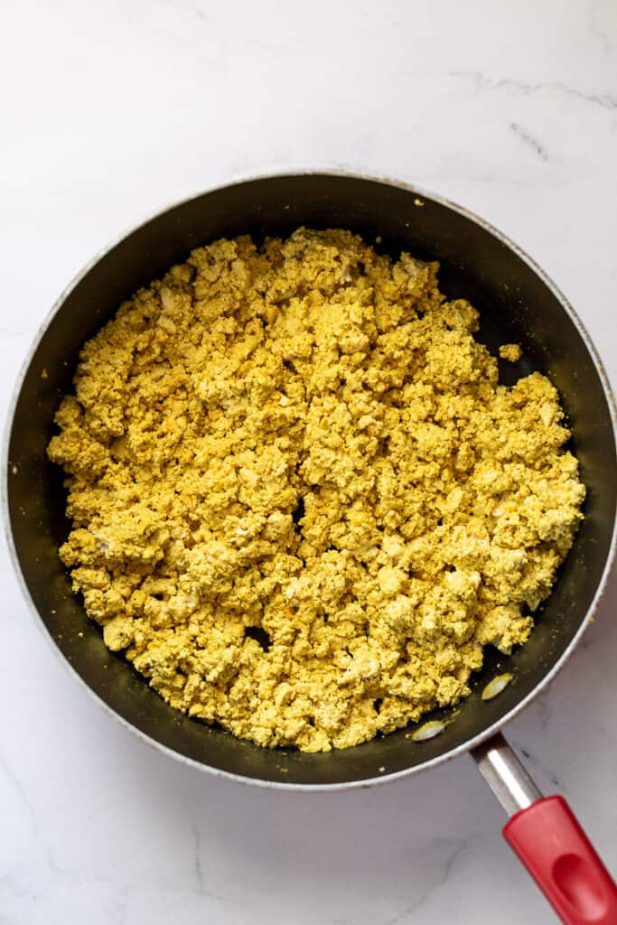 This 10-minute tofu scramble recipe is a satisfying plant-based breakfast with nutritional yeast, turmeric, and garlic for spice and flavor. Overhead view of an easy tofu scramble in a skillet.