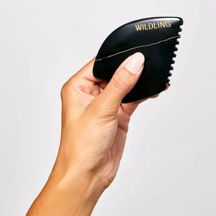 hand holding a black gua sha stone from wildling beauty