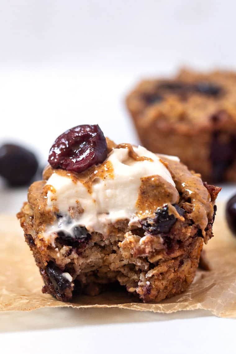 close up baked oatmeal cups with cherries, almond and vanilla topped with yogurt and almond butter