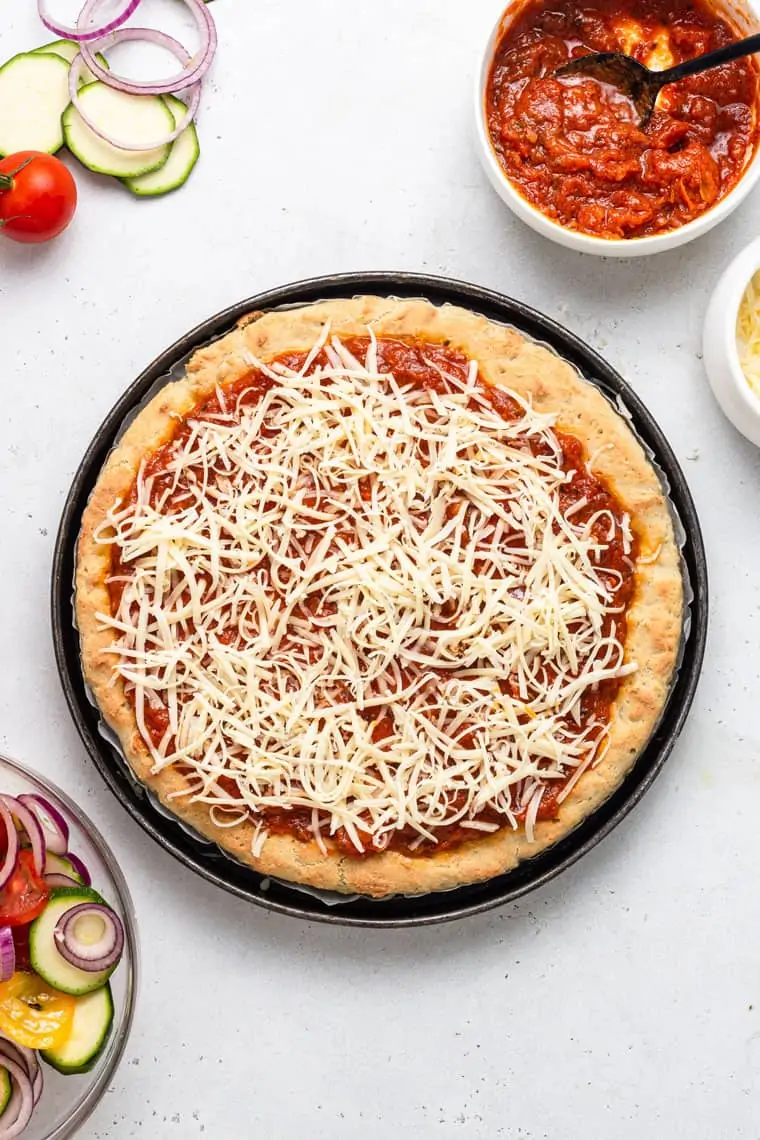 overhead of unbaked gluten-free pizza crust with sauce and cheese