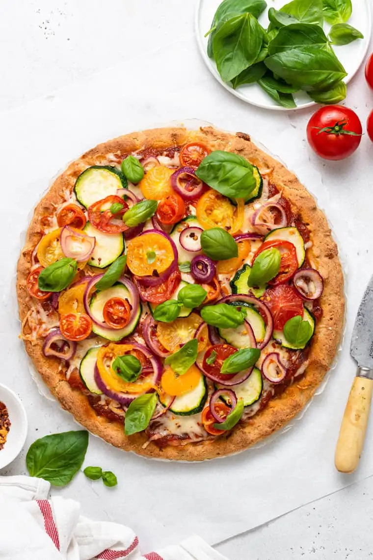 overhead of glutne free vegetable pizza with fresh herbs and tomatoes