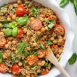 overhead of white bowl with quinoa caprese salad and fresh basil