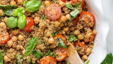 overhead of white bowl with quinoa caprese salad and fresh basil