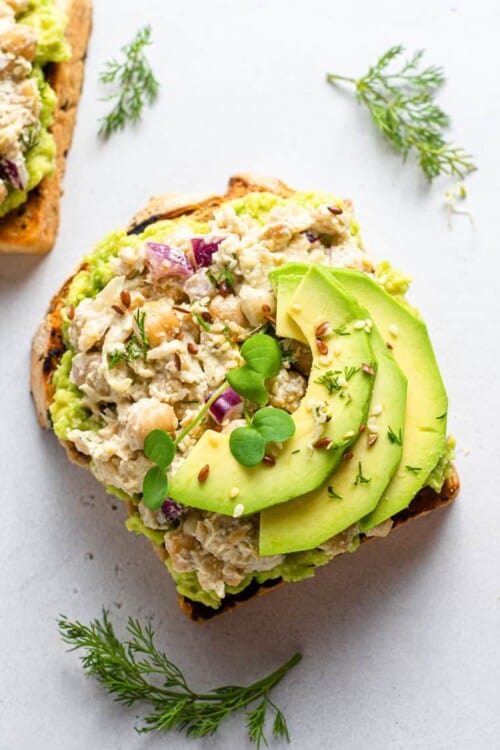 overhead of a slice of toast with smashed chickpea salad and avocado slices