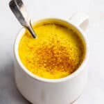 overhead of a white mug with golden milk latte dusted with cinnamon