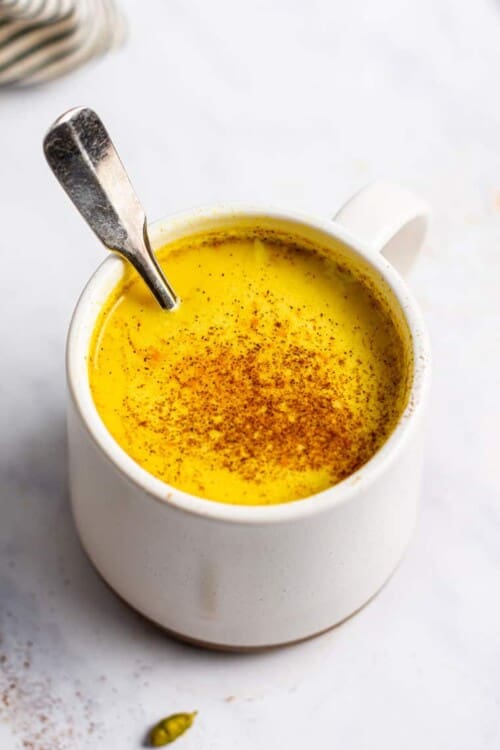 overhead of a white mug with golden milk latte dusted with cinnamon