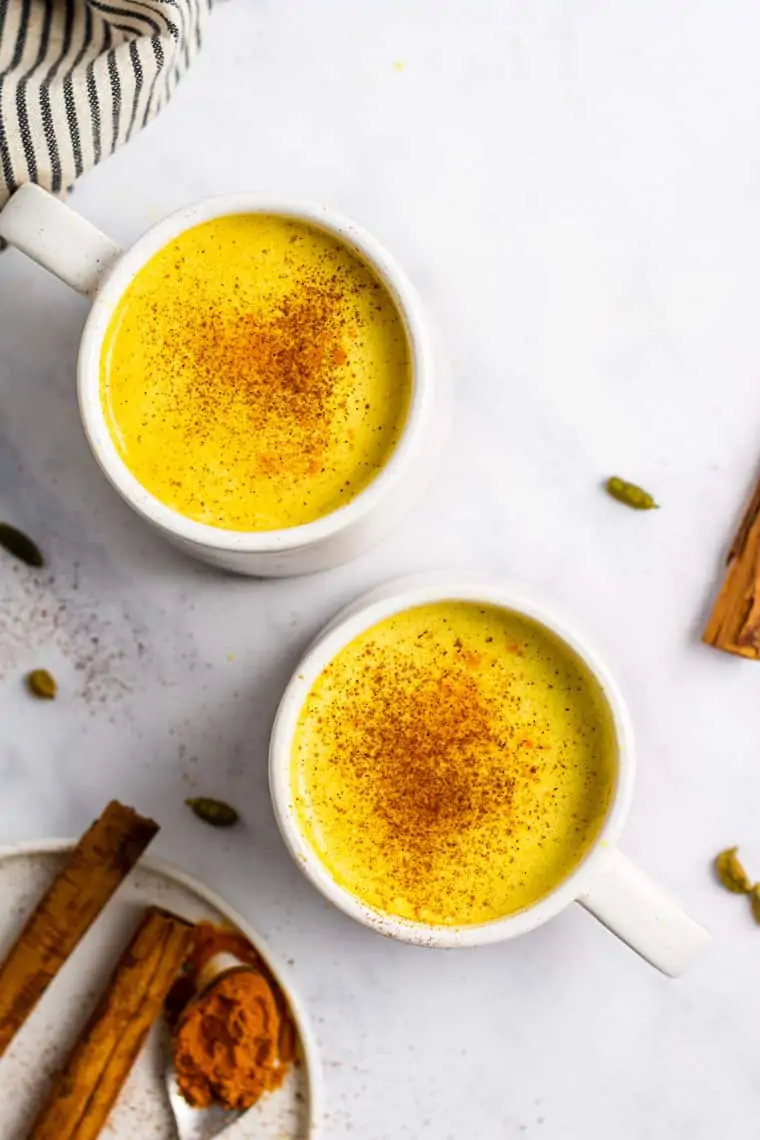 overhead of two white mugs with turmeric lattes