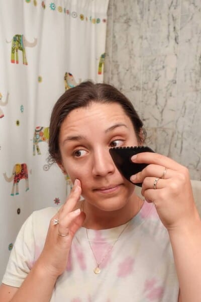 woman using black gua sha tool under eye