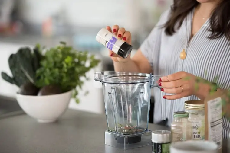 woman pouring monk fruit sweetener into a plastic blender