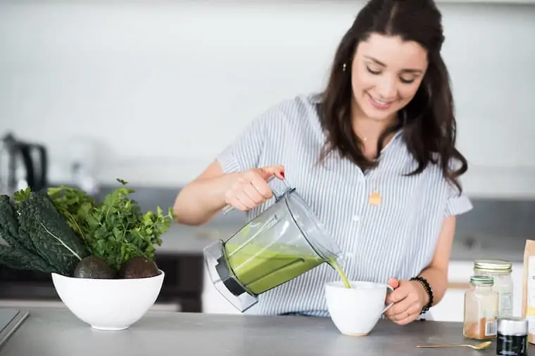 alyssa pouring a green matcha latte from a blender into a mug