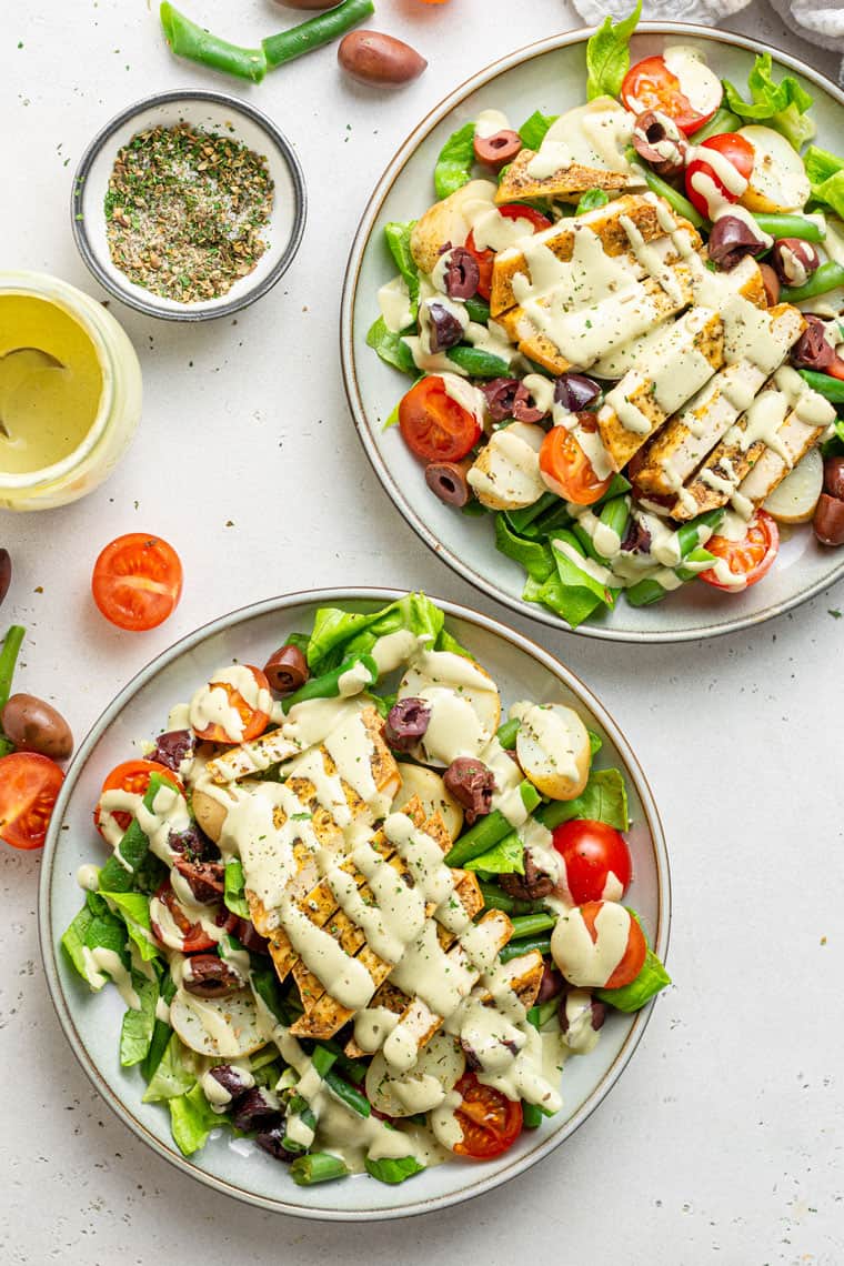 overhead of two bowls of tofu salad with olives, tomatoes and potatoes with creamy dressing