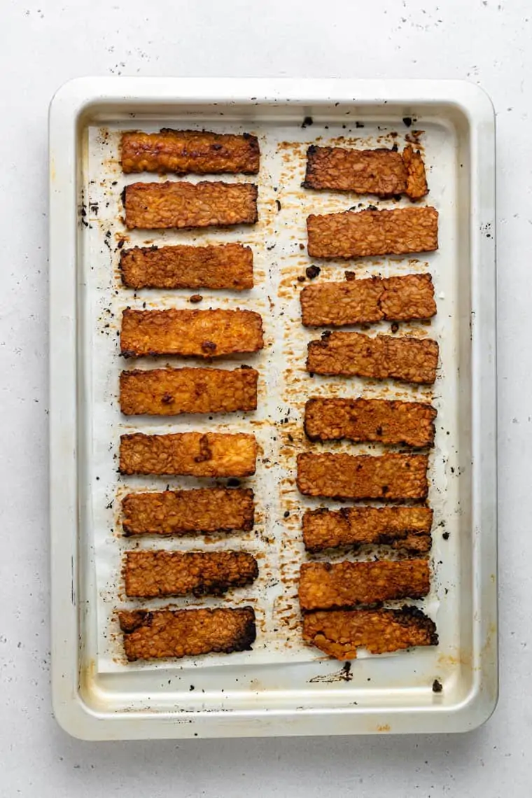 overhead of a baking sheet with two rows of tempeh bacon