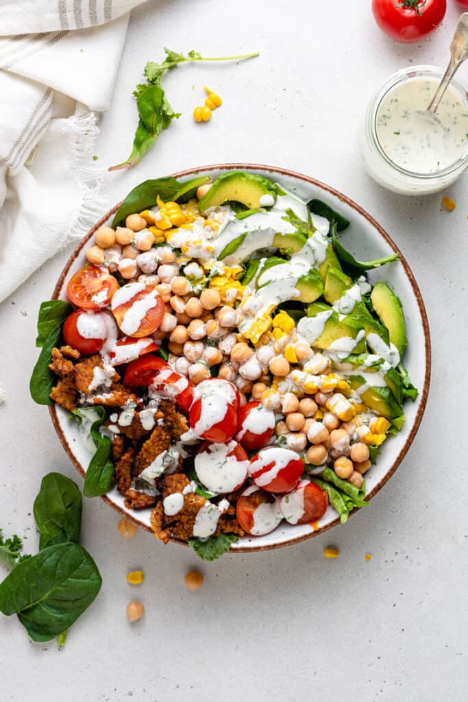 overhead of a white bowl with vegan cobb salad topped with creamy dressing