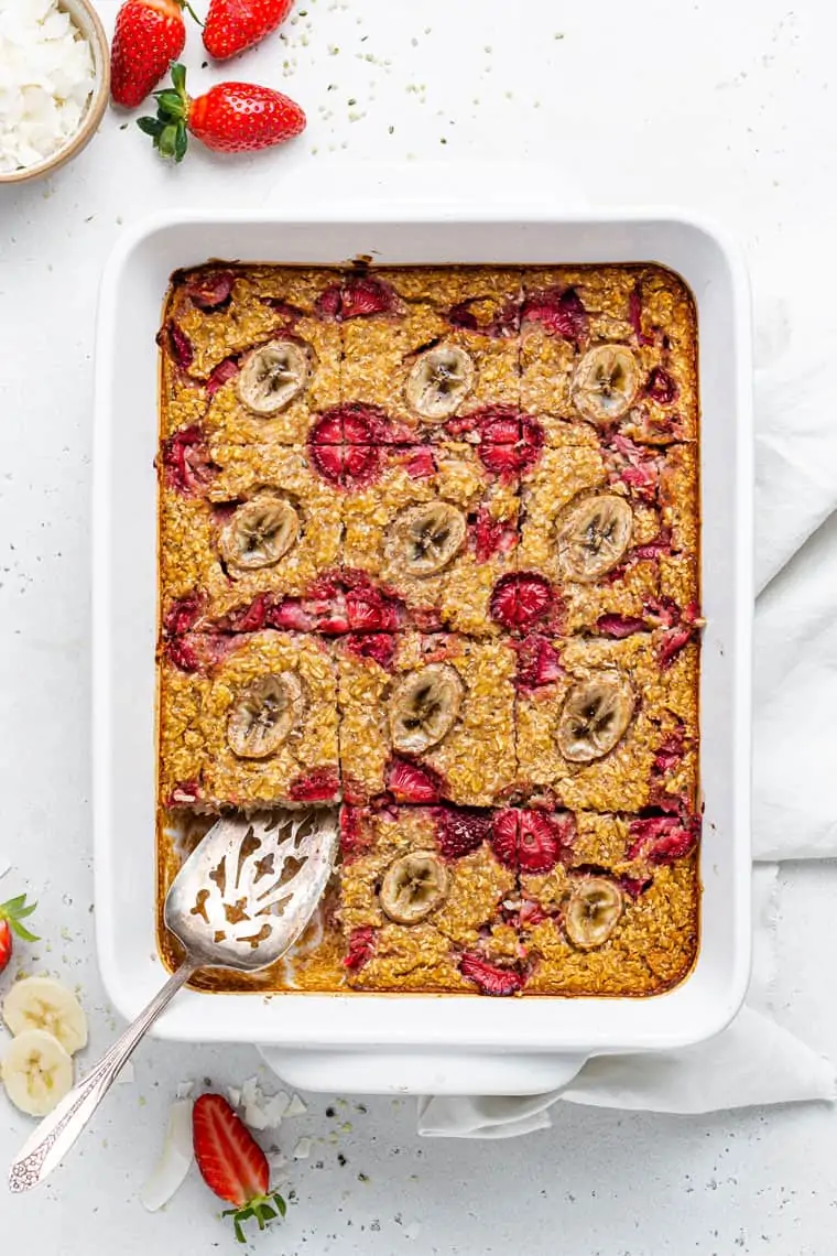 overhead of a baking dish of baked strawberry banana oats with a metal spoon