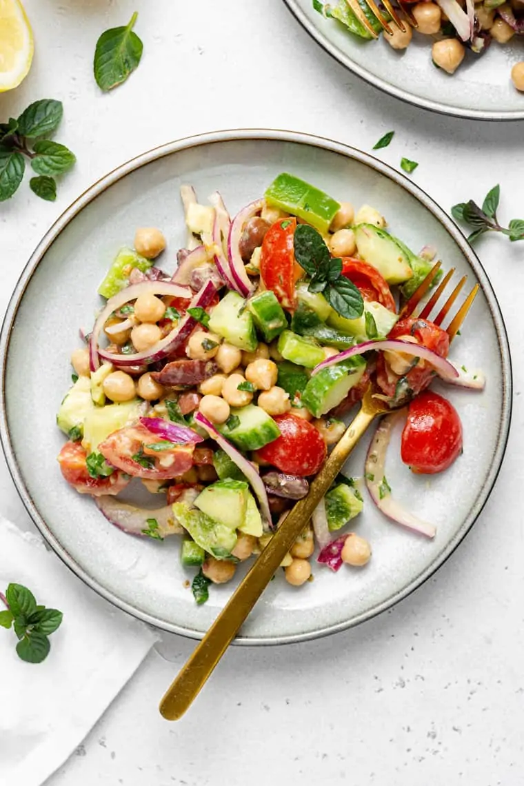 white plate with a serving of garbanzo bean salad with vegetables