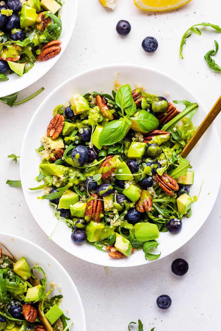overhead of a white bowl with quinoa blueberry power salad with dressing
