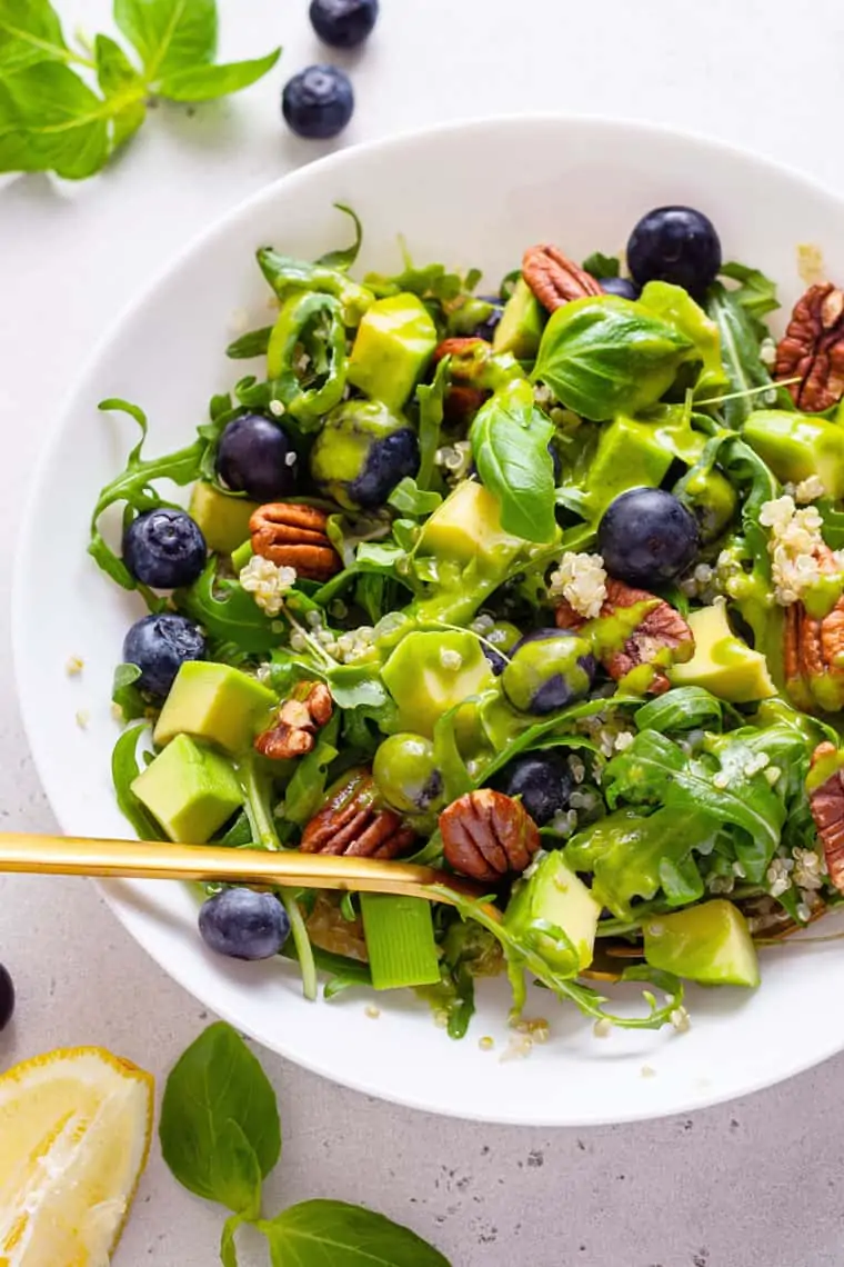white bowl of blueberry power salad with dressing on top