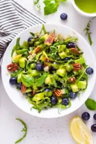 white bowl of blueberry, pecan, quinoa and arugula salad