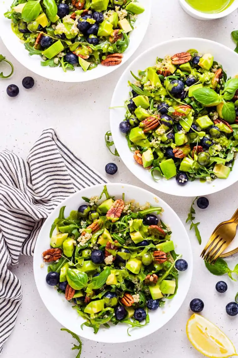 three white bowls with blueberry quinoa and arugula salad