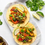 overhead of a marble platter with two vegan tempeh fajitas