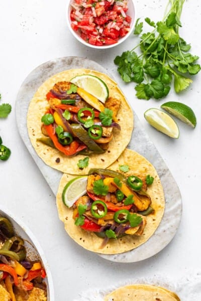 overhead of a marble platter with two vegan tempeh fajitas