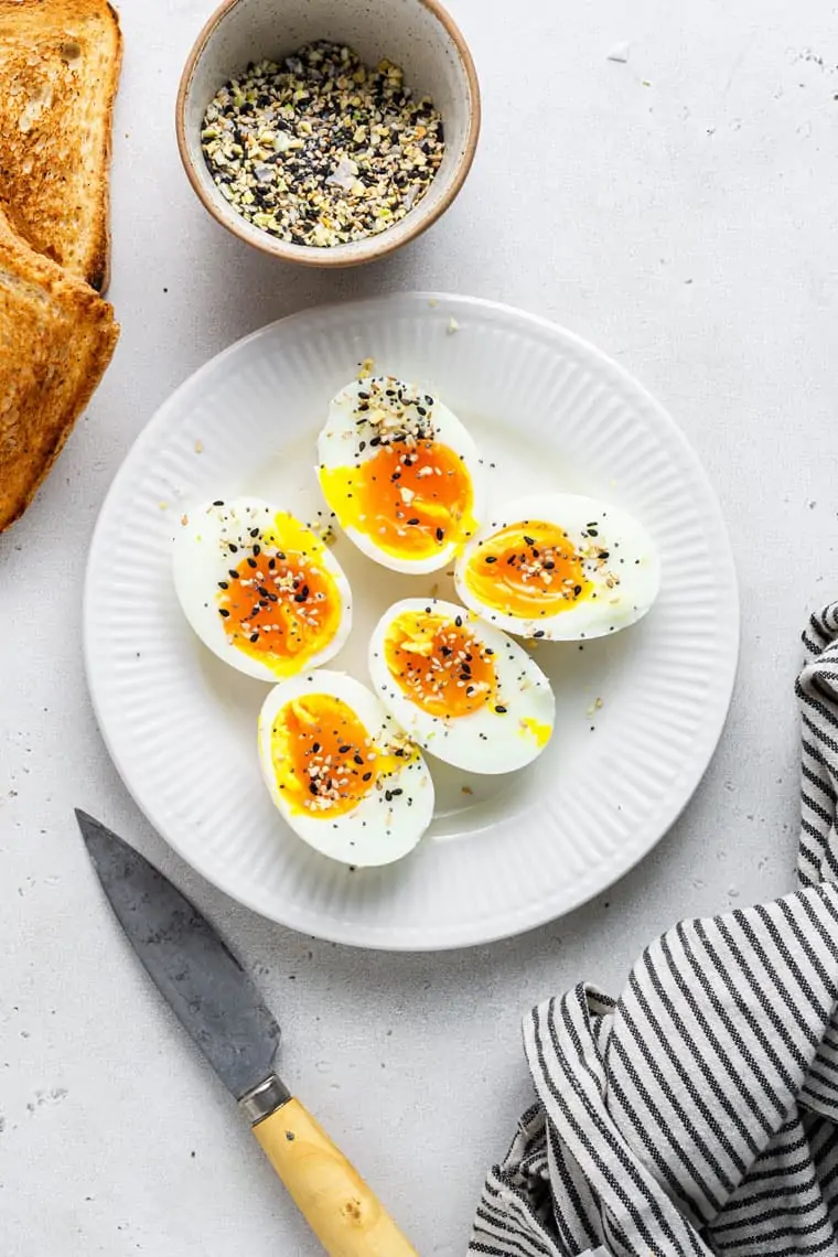 overhead of a white plate with jammy soft boiled eggs topped with everything bagel seasoning